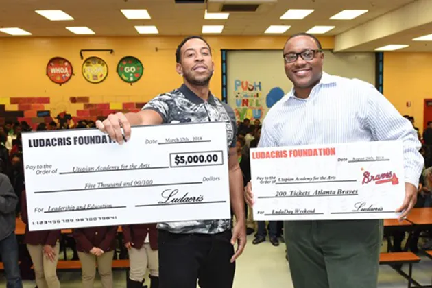 Ludacris poses with a check donated to the Utopian Academy for the Arts.